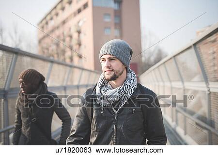 Stock Image - Two young men strolling on footbridge. Fotosearch