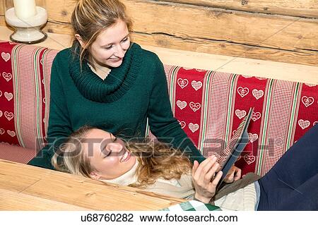 Two young women using touchscreen on digital tablet in log cabin View Large Photo Image Stock Image - Two young women using touchscreen on digital tablet in log cabin. Fotosearch