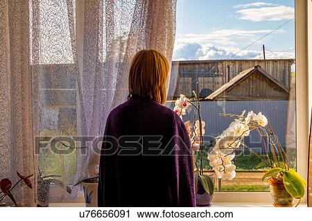 Woman looking out at agricultural building from living room window View Large Photo Image Stock Image - Woman looking out at agricultural building from living room window. Fotosearch