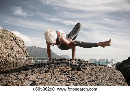 Stock Image - Woman practising yoga by ocean, Cape Town, South Africa. Fotosearch