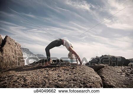 Stock Image - Woman practising yoga by ocean, Cape Town, South Africa. Fotosearch
