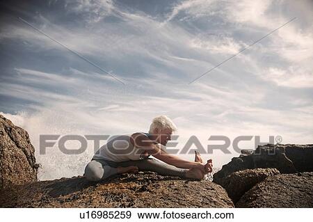 Stock Photo - Woman practising yoga by ocean, Cape Town, South Africa. Fotosearch