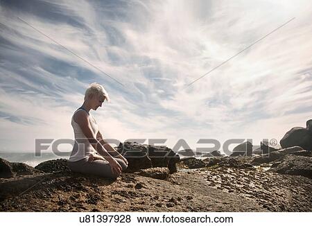 Stock Photo - Woman practising yoga by ocean, Cape Town, South Africa. Fotosearch