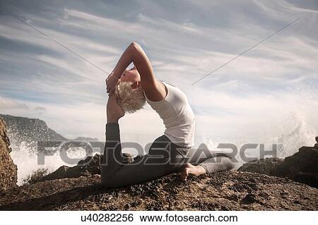 Stock Photograph - Woman practising yoga by ocean, Cape Town, South Africa. Fotosearch