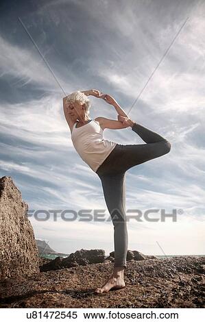 Stock Photography - Woman practising yoga by ocean, Cape Town, South Africa. Fotosearch