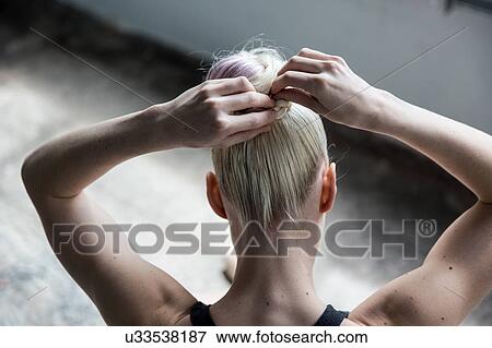 Woman tying up hair in studio View Large Photo Image Stock Photo - Woman tying up hair in studio. Fotosearch