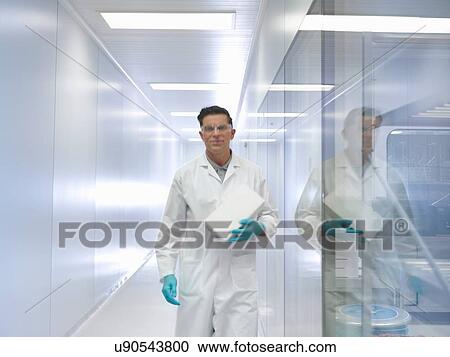 Stock Image - Worker carrying orthopaedic medical product box through corridor in clean room. Fotosearch