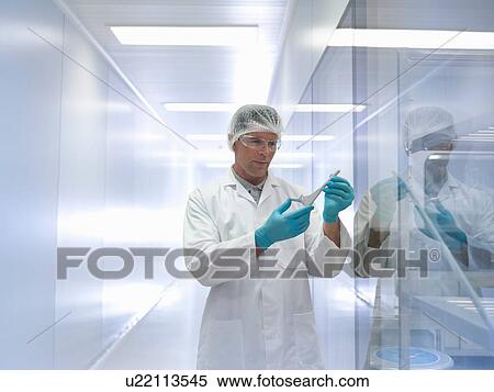 Stock Photography - Worker holding orthopaedic hip stem replacement in clean room. Fotosearch