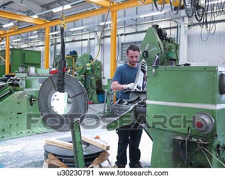 Worker loading rolls of metal into stamping machine in engineering factory View Large Photo Image Stock Image - Worker loading rolls of metal into stamping machine in engineering factory. Fotosearch
