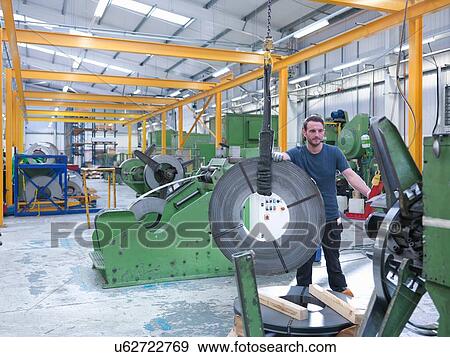 Worker loading rolls of metal into stamping machine in engineering factory View Large Photo Image Stock Photo - Worker loading rolls of metal into stamping machine in engineering factory. Fotosearch