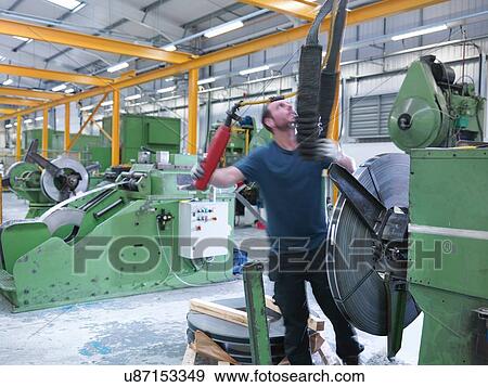Worker loading rolls of metal into stamping machine in engineering factory View Large Photo Image Stock Photo - Worker loading rolls of metal into stamping machine in engineering factory. Fotosearch