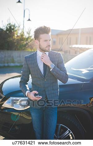 Young businessman adjusting tie in car park View Large Photo Image Stock Image - Young businessman adjusting tie in car park. Fotosearch