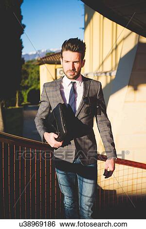 Stock Photograph - Young businessman carrying briefcase on footbridge. Fotosearch