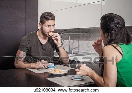 Young couple drinking coffee and eating biscuits at breakfast bar View Large Photo Image Picture - Young couple drinking coffee and eating biscuits at breakfast bar. Fotosearch