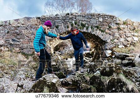 Stock Photograph - Young couple hiking, Ashness Bridge, Keswick, Lake District, Cumbria, United Kingdom. Fotosearch