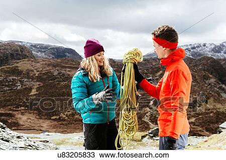 Stock Image - Young couple hiking, holding safety rope, Honister Slate Mine, Keswick, Lake District, Cumbria, United Kingdom. Fotosearch