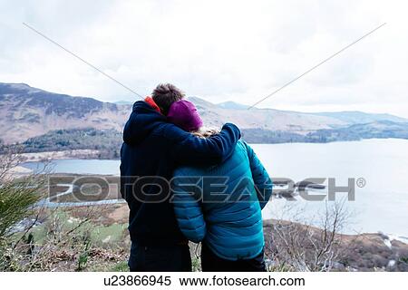 Young couple hiking, looking at view, rear view, Derwent Water, Keswick, Lake District, Cumbria, United Kingdom View Large Photo Image Stock Photography - Young couple hiking, looking at view, rear view, Derwent Water, Keswick, Lake District, Cumbria, United Kingdom. Fotosearch