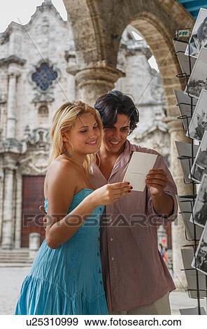 Young couple looking at postcards in the Plaza de la Cathedral of Havana, Cuba View Large Photo Image Stock Photo - Young couple looking at postcards in the Plaza de la Cathedral of Havana, Cuba. Fotosearch