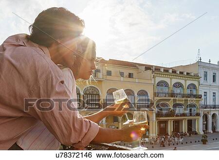 Stock Photograph - Young couple looking out from restaurant balcony in Plaza Vieja, Havana, Cuba. Fotosearch