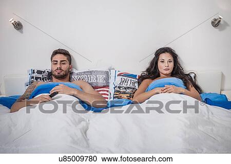 Young couple lying in bed sulking View Large Photo Image Stock Image - Young couple lying in bed sulking. Fotosearch