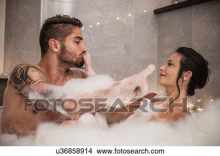 Picture - Young couple playing with bubbles in bubble bath. Fotosearch