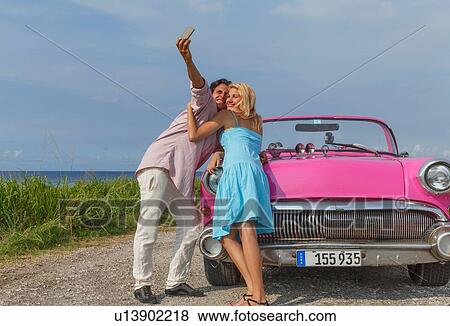 Young couple posing for selfie with vintage convertible, Havana, Cuba View Large Photo Image Stock Photo - Young couple posing for selfie with vintage convertible, Havana, Cuba. Fotosearch
