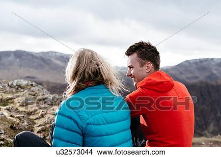 Picture - Young couple sitting on hilltop, rear view, Keswick, Lake District, Cumbria, United Kingdom. Fotosearch
