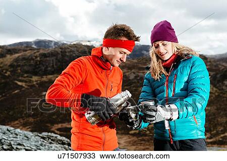 Young couple taking a break from hiking, having hot drink from drinks flask, Honister Slate Mine, Keswick, Lake District, Cumbria, United Kingdom View Large Photo Image Stock Image - Young couple taking a break from hiking, having hot drink from drinks flask, Honister Slate Mine, Keswick, Lake District, Cumbria, United Kingdom. Fotosearch