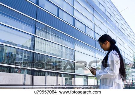 Young female scientist looking at digital tablet outside laboratory View Large Photo Image Picture - Young female scientist looking at digital tablet outside laboratory. Fotosearch