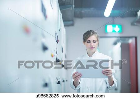 Young female scientist reading paperwork in technical room View Large Photo Image Stock Photography - Young female scientist reading paperwork in technical room. Fotosearch