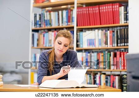 Young female student reading textbook at library desk View Large Photo Image Stock Photography - Young female student reading textbook at library desk. Fotosearch