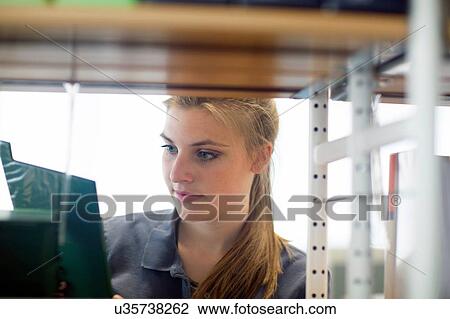 Young female student searching for textbook in library View Large Photo Image Stock Image - Young female student searching for textbook in library. Fotosearch