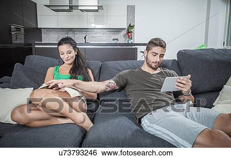 Young man covering girlfriends book on sofa View Large Photo Image Stock Photograph - Young man covering girlfriends book on sofa. Fotosearch
