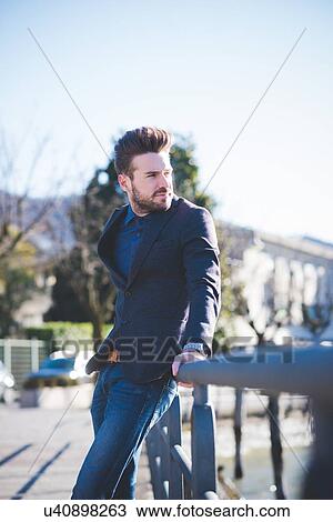 Young man leaning against railing and looking over his shoulder View Large Photo Image Stock Image - Young man leaning against railing and looking over his shoulder. Fotosearch