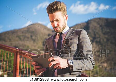 Young man on footbridge reading digital tablet, Rovato, Brescia, Italy View Large Photo Image Stock Image - Young man on footbridge reading digital tablet, Rovato, Brescia, Italy. Fotosearch