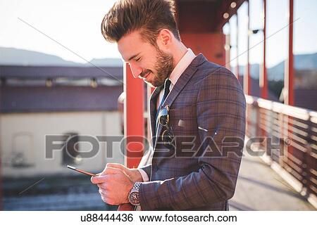 Young man reading smartphone texts on footbridge View Large Photo Image Stock Photograph - Young man reading smartphone texts on footbridge. Fotosearch