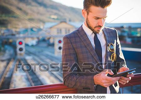 Young man with using digital tablet on railway footbridge View Large Photo Image Stock Photo - Young man with using digital tablet on railway footbridge. Fotosearch