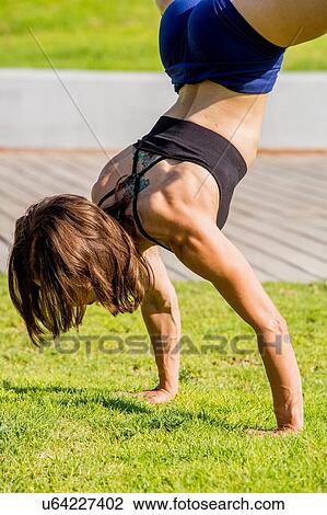 Young woman doing handstand in park View Large Photo Image Stock Image - Young woman doing handstand in park. Fotosearch