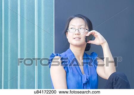 Young woman in front of wall talking on smartphone View Large Photo Image Stock Image - Young woman in front of wall talking on smartphone. Fotosearch