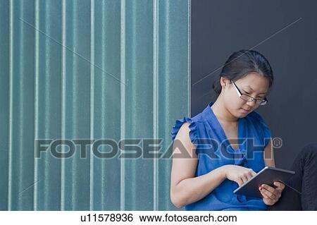 Young woman in front of wall using touchscreen on digital tablet View Large Photo Image Stock Photograph - Young woman in front of wall using touchscreen on digital tablet. Fotosearch