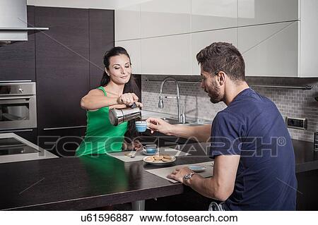 Stock Photo - Young woman pouring breakfast coffee for boyfriend. Fotosearch