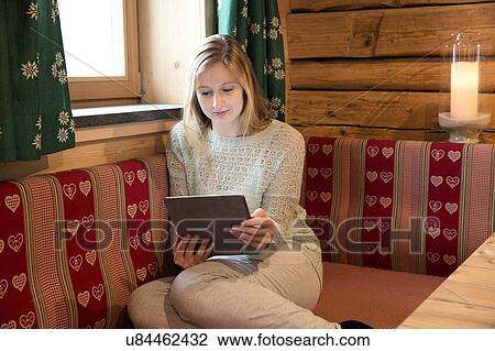 Young woman reading digital tablet in log cabin View Large Photo Image Stock Image - Young woman reading digital tablet in log cabin. Fotosearch