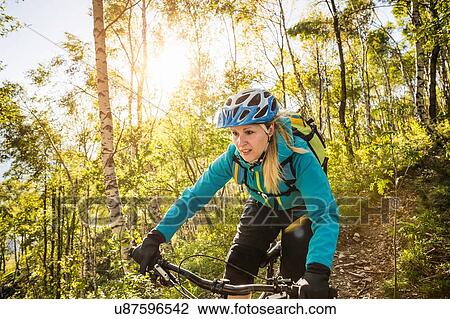 Young woman riding mountain bike through woods, Lake Como, Italy View Large Photo Image Stock Image - Young woman riding mountain bike through woods, Lake Como, Italy. Fotosearch