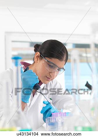 Young woman scientist pipetting sample into vial in a laboratory used for chemical and DNA testing View Large Photo Image Picture - Young woman scientist pipetting sample into vial in a laboratory used for chemical and DNA testing. Fotosearch