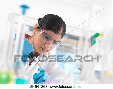 Stock Photo - Young woman scientist pipetting sample into vial in a laboratory used for chemical and DNA testing. Fotosearch