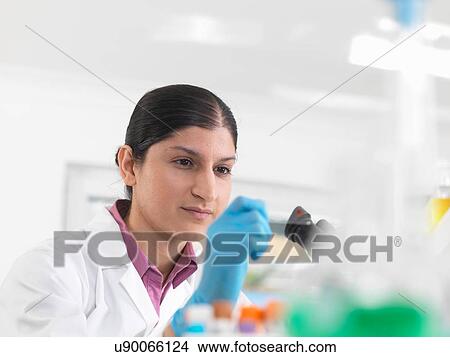 Young woman scientist viewing blood slide during clinical testing of medical samples in a laboratory View Large Photo Image Picture - Young woman scientist viewing blood slide during clinical testing of medical samples in a laboratory. Fotosearch
