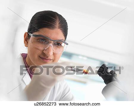 Stock Image - Young woman scientist viewing blood sample during clinical testing of medical samples in a laboratory. Fotosearch