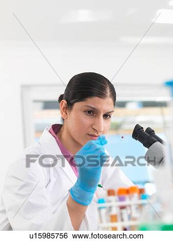 Stock Photograph - Young woman scientist viewing blood slide during clinical testing of medical samples in a laboratory. Fotosearch