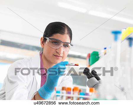 Stock Photograph - Young woman scientist viewing blood tube during clinical testing of medical samples in a laboratory. Fotosearch