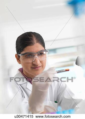 Stock Photography - Young woman scientist viewing blood sample during clinical testing of medical samples in a laboratory. Fotosearch
